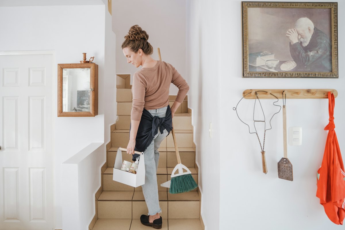 Lovely Maid housekeeper carrying cleaning supplies up the stairs of a Springfield home