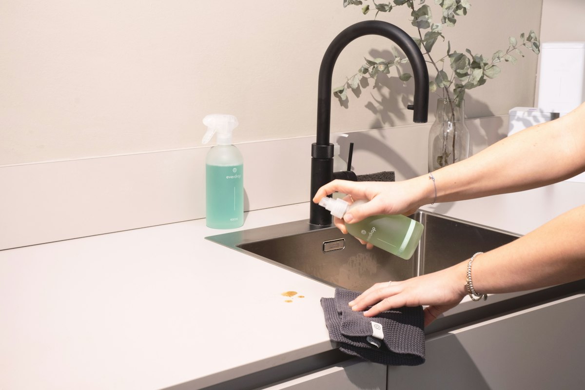 Cleaner wiping a kitchen sink and countertop during a targeted room cleaning