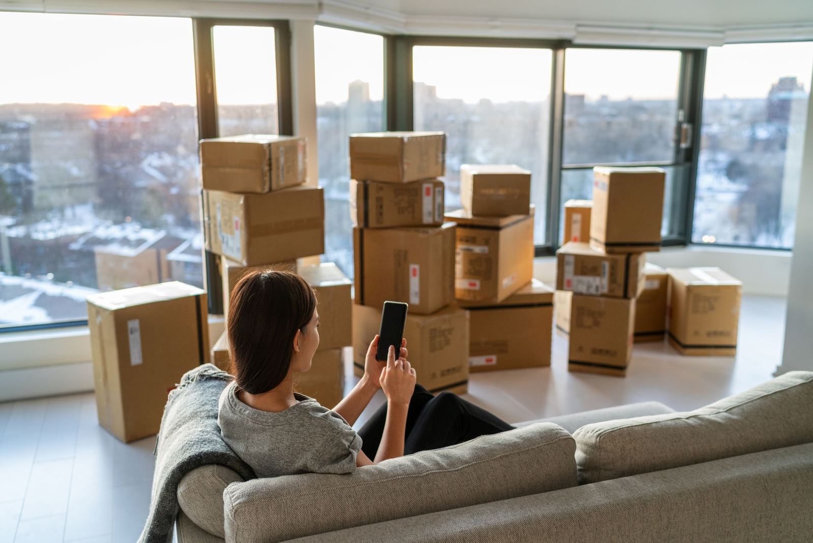 Woman resting on a couch surrounded by moving boxes on moving day