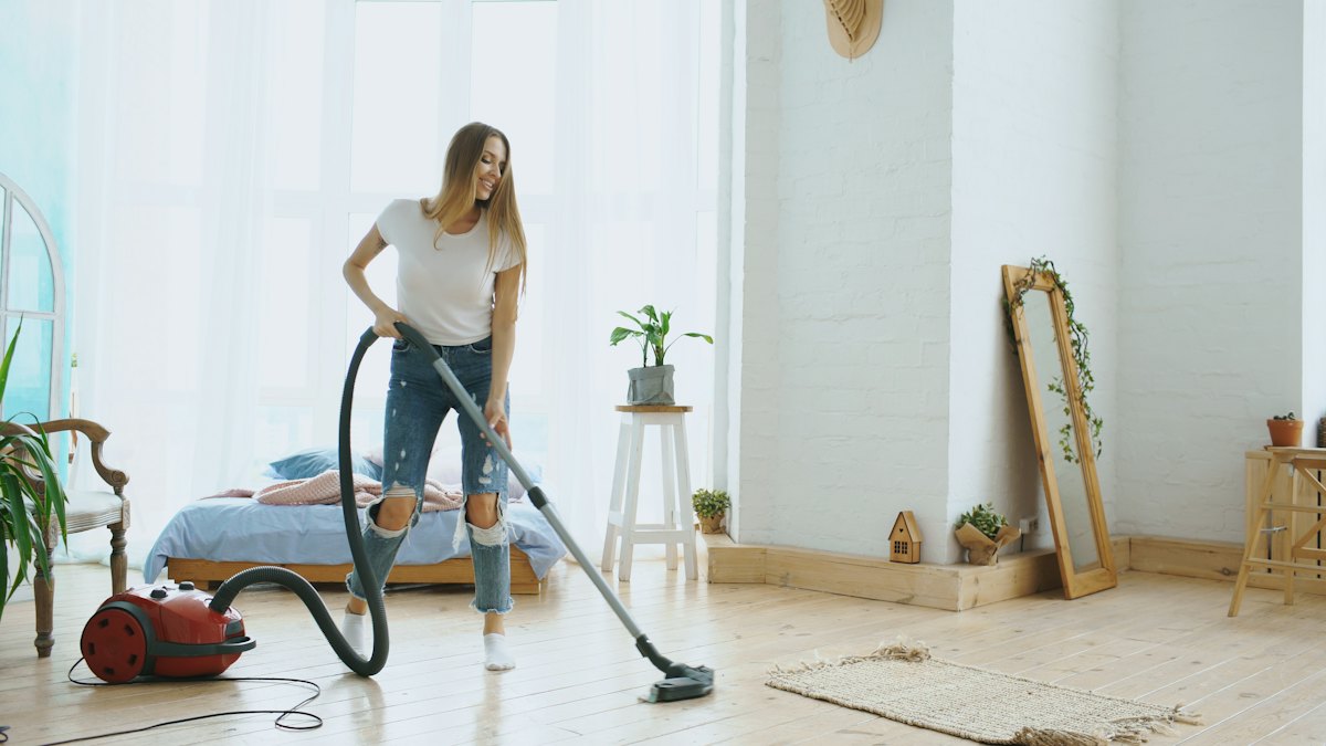 Cleaner vacuuming the hardwood floor of a bright living room in Springfield, VA