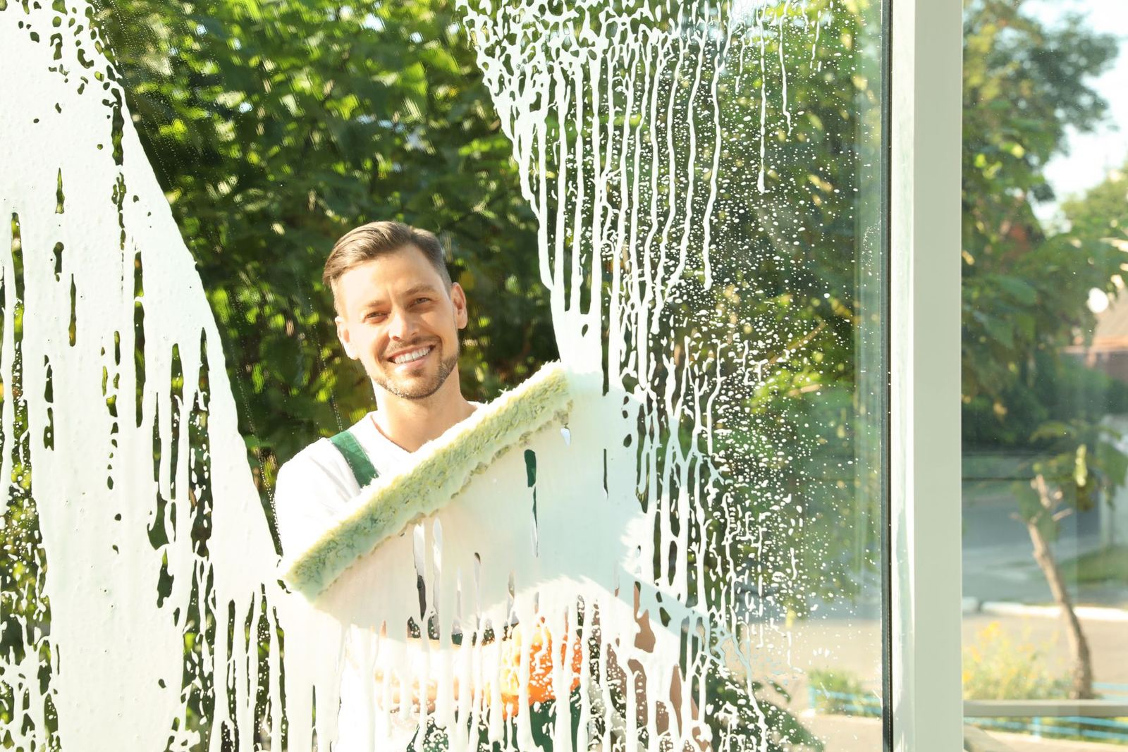 Professional cleaner washing a window with a sponge for a streak-free shine